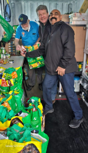 District Deputy Trevor Philips helps State Deputy Bruce S., Poulin and Bill Graham fill some of the bags with food to be distributed later in the day.